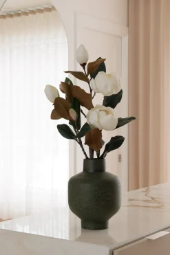 Artificial white magnolia flowers in a green vase